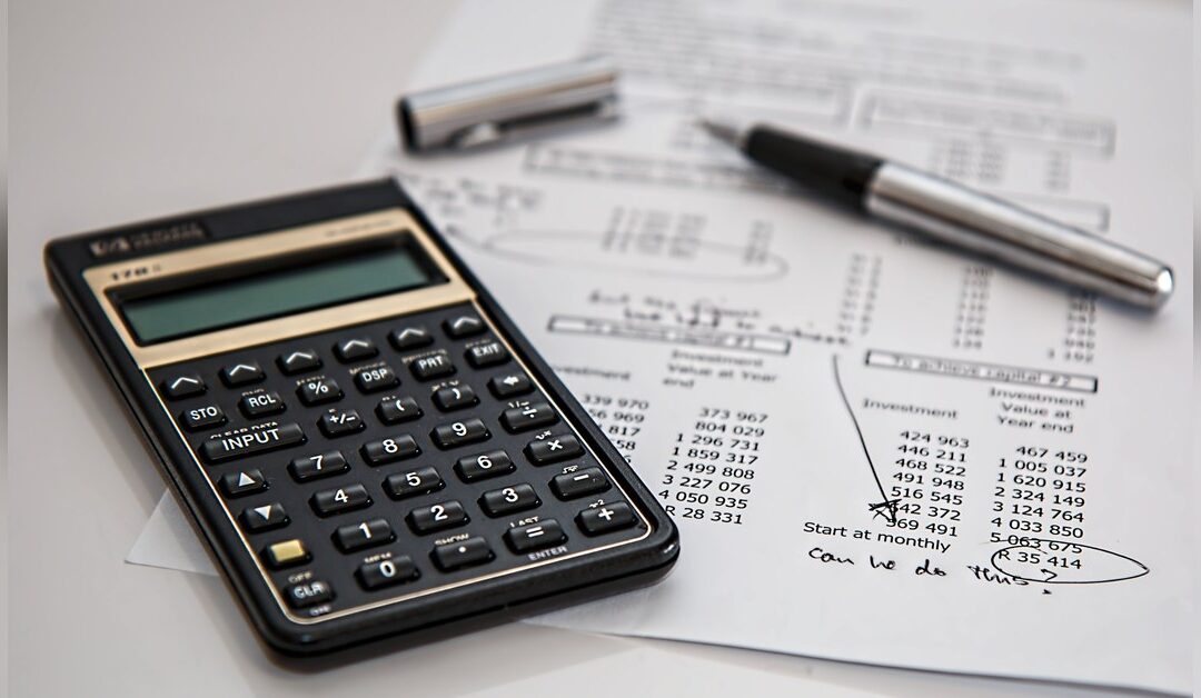 Calculator and pen on an itemized financial worksheet, checking the numbers on an insurance estimate