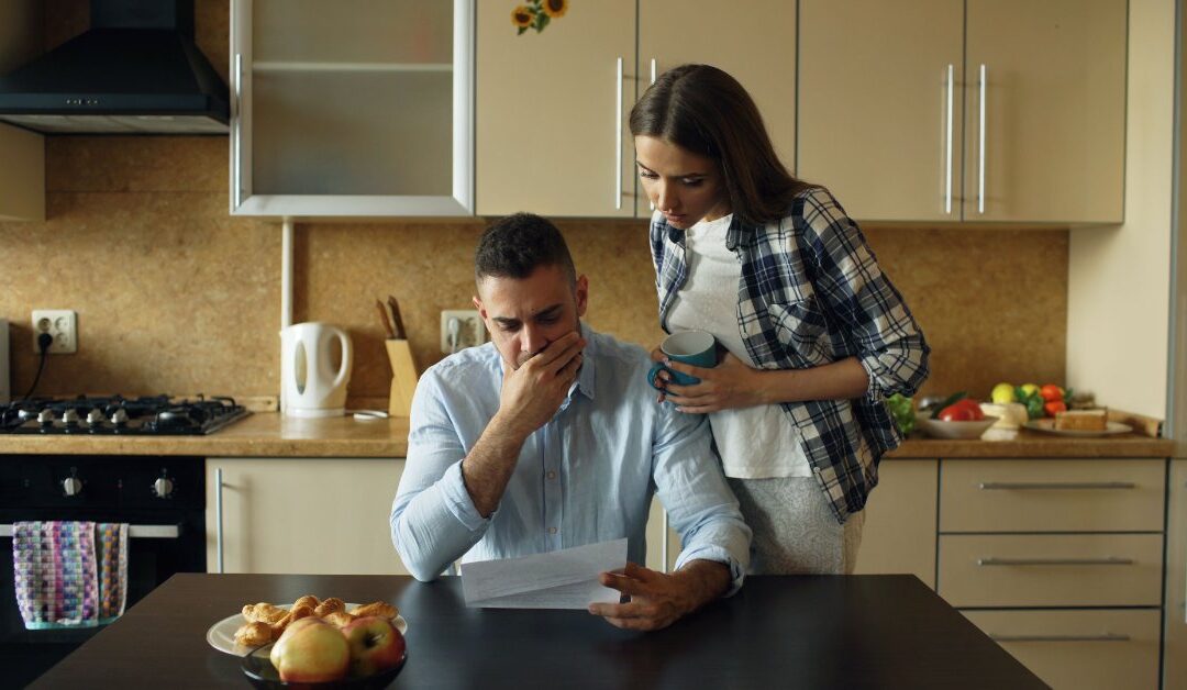 Worried couple reading an insurance claim denial letter together in their kitchen