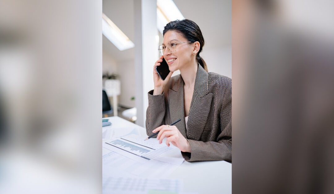Woman on a phone call while looking at insurance claim paperwork at a table